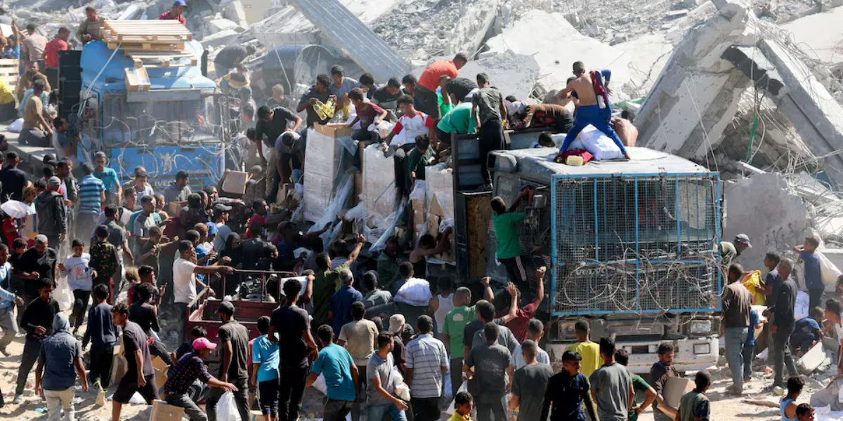 Palestinos recolhem suprimentos de ajuda de caminhões que entraram em Gaza, em meio a um cessar-fogo entre Israel e o Hamas, em Khan Younis, no sul da Faixa de Gaza, em 12 de outubro de 2025. REUTERS/Ramadan Abed