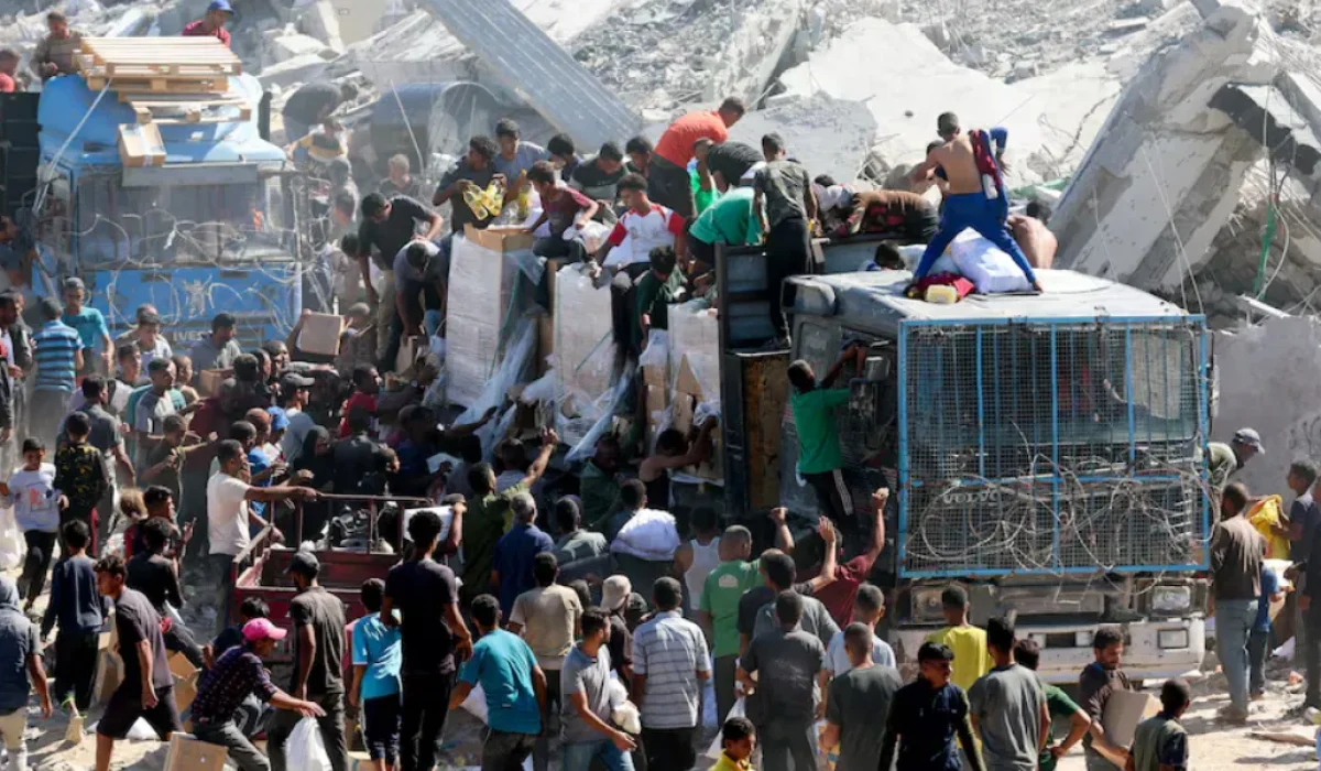 Palestinos recolhem suprimentos de ajuda de caminhões que entraram em Gaza, em meio a um cessar-fogo entre Israel e o Hamas, em Khan Younis, no sul da Faixa de Gaza, em 12 de outubro de 2025. REUTERS/Ramadan Abed